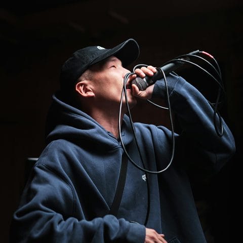 Rapper pemula mengenakan hoodie dan topi sedang tampil di panggung musik hip hop
