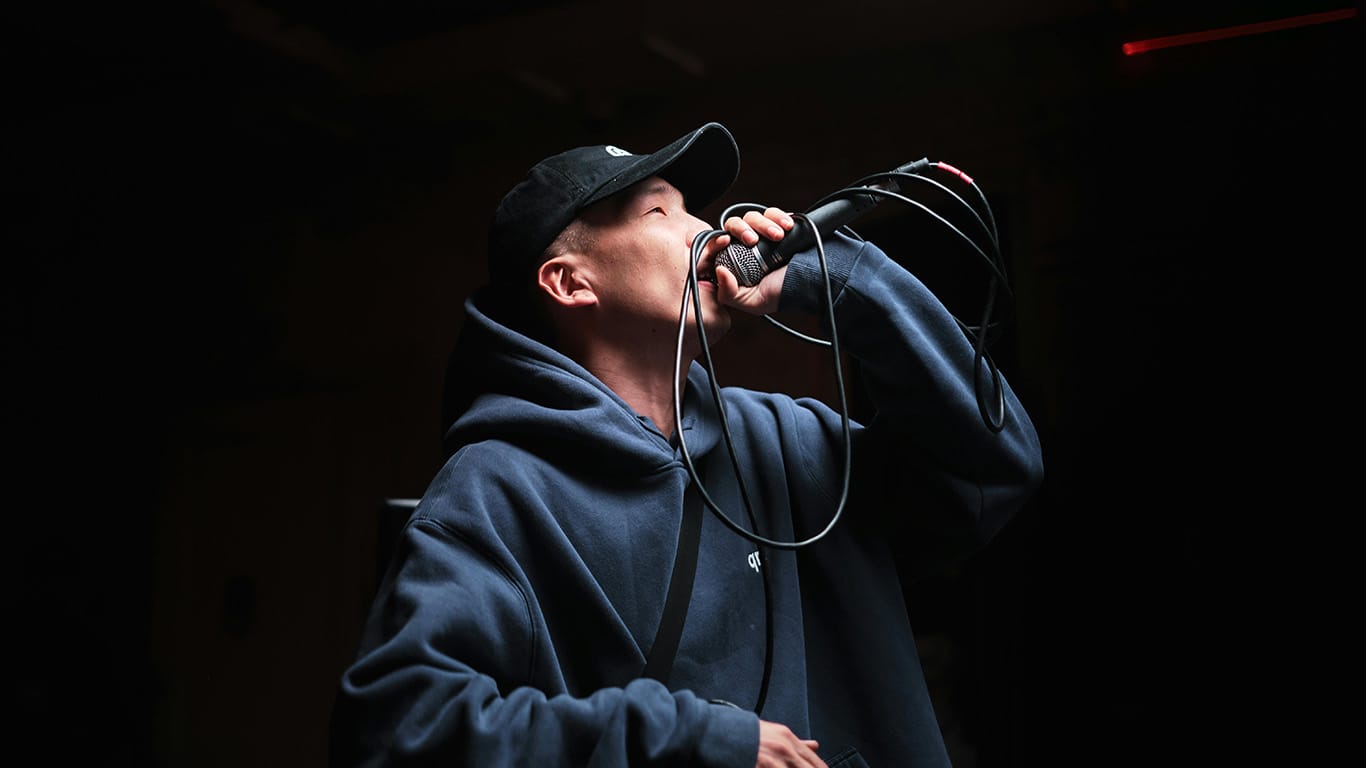 Rapper pemula mengenakan hoodie dan topi sedang tampil di panggung musik hip hop