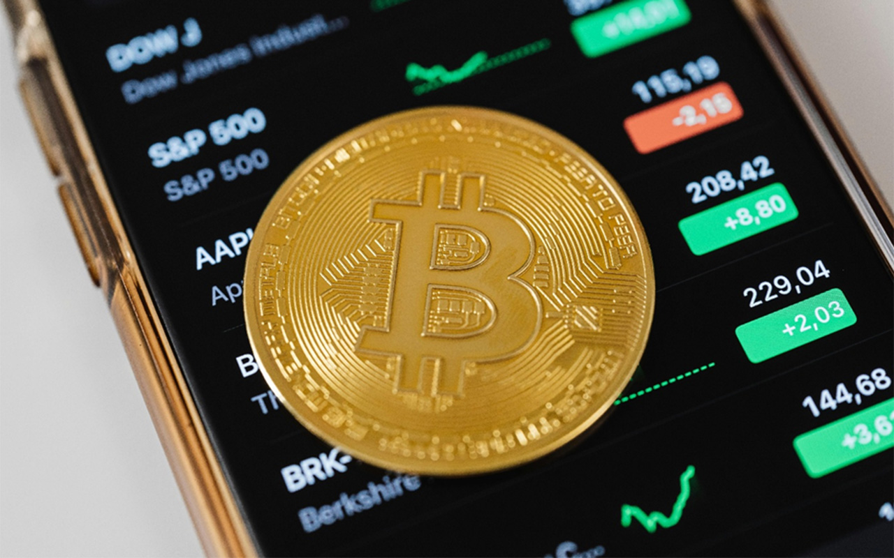 Bitcoin dengan latar belakang grafik harga kripto sebagai ilustrasi investasi crypto untuk pemula