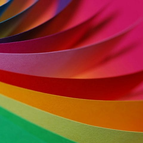 Close up lembaran kertas berwarna-warni sebagai ilustrasi konsep color photography dalam seni fotografi