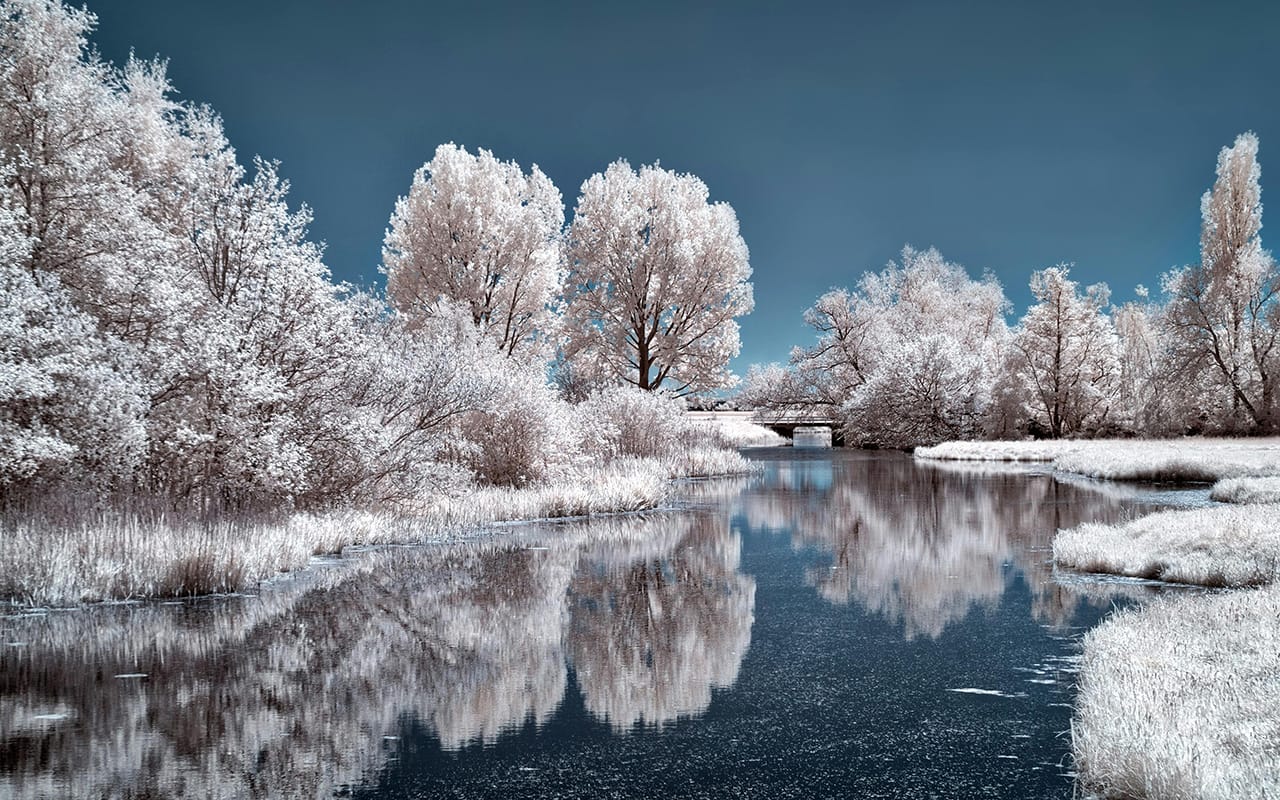 Contoh hasil infrared photography pemandangan sungai dan pepohonan dengan efek warna putih dan langit biru