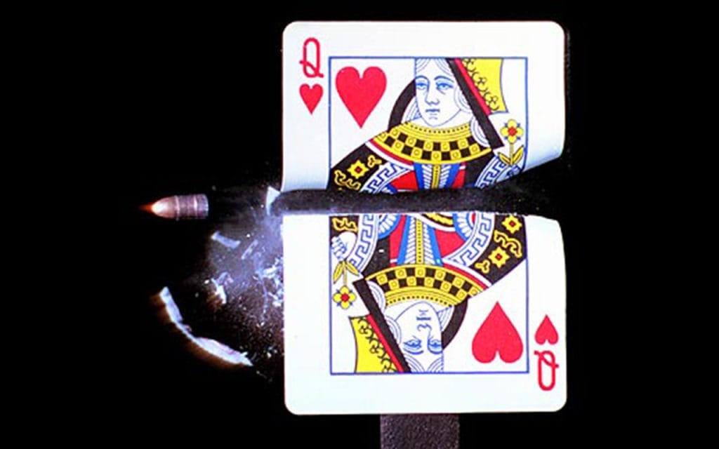 Peluru menembus kartu remi ratu hati dalam foto berkecepatan tinggi, contoh fotografi balistik yang menangkap momen cepat secara detail