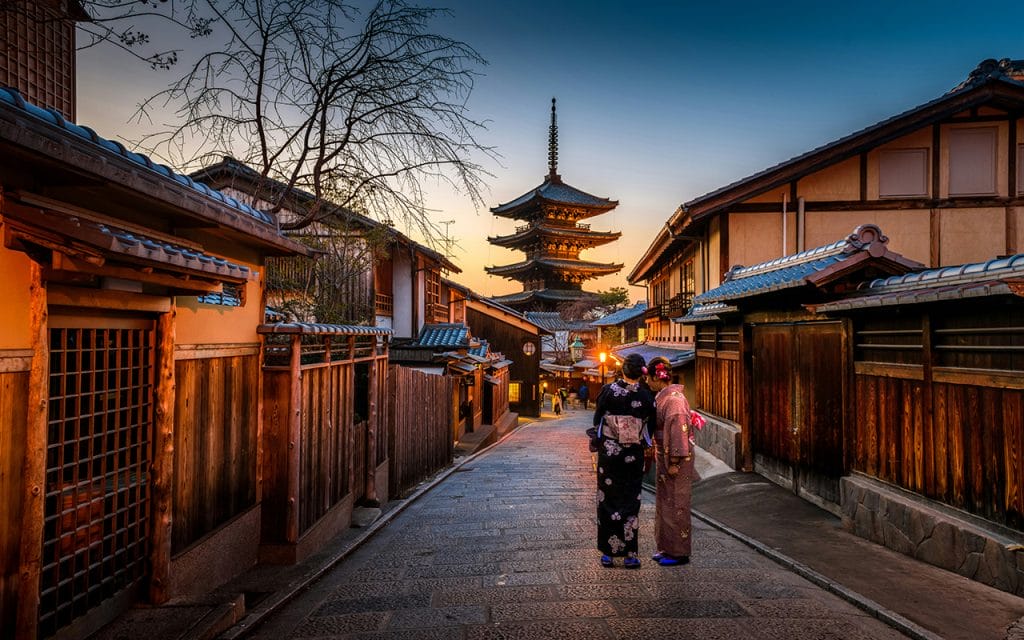 Fotografi perjalanan jalan tradisional di Jepang dengan dua wanita mengenakan kimono saat senja