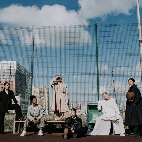 Sekelompok wanita berpose di depan pagar logam dengan latar gedung kota, menampilkan gaya hidup modern dalam konsep lifestyle photography
