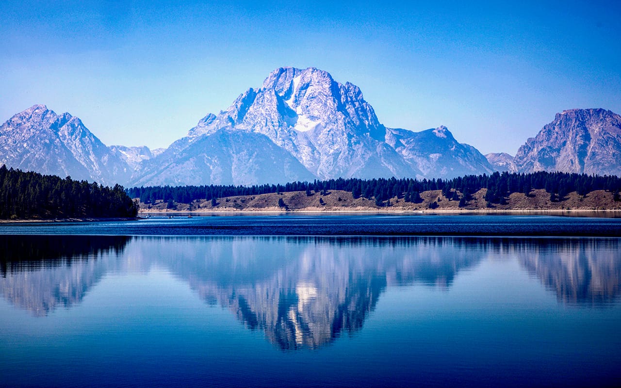 Pemandangan pegunungan dan danau tenang dengan pantulan gunung di air – contoh landscape photography alam