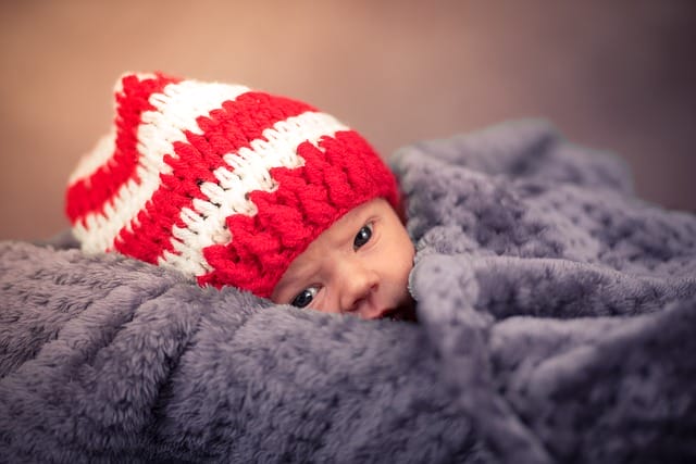 Bayi berbaring di atas selimut lembut saat sesi newborn photography