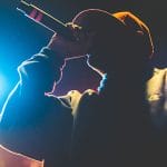 Seorang rapper sedang tampil di panggung dengan mikrofon