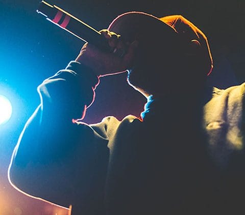 Seorang rapper sedang tampil di panggung dengan mikrofon