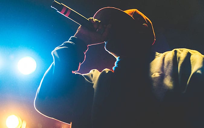 Seorang rapper sedang tampil di panggung dengan mikrofon