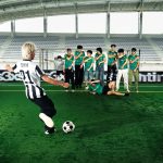 Cover album Liga Besar karya Tenxi menampilkan suasana stadion sepak bola dengan Tenxi bersiap menendang bola ke arah sekelompok pemain.
